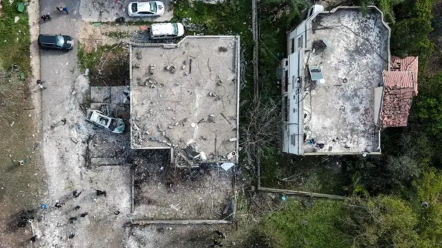 A drone view shows two destroyed buildings and several damaged cars from above
