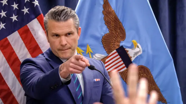 Pete Hegseth points towards a raised hand as he speaks during a press conference