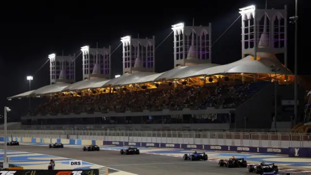 Cars drive around a stadium at night