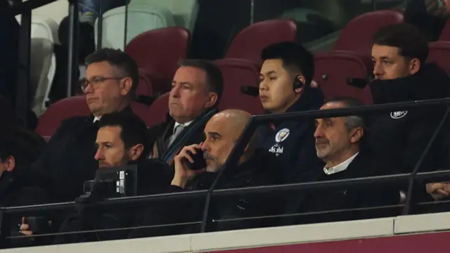 Pep Guardiola on the phone in the stands