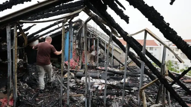 People inspect the damage at the site of a reported overnight missile strike in a residential area near the city of Shoham, central Israel