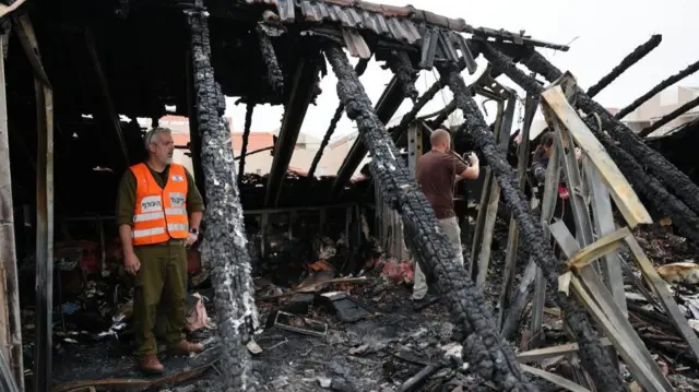 Home Front Command members and emergency services inspect the damage after a reported overnight missile strike hit a residential area near the city of Shoham, central Israel