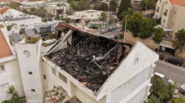 The top floor of an apartment has been completely burnt and destroyed. The outside of the structure show where the roof used to sit as rubble lies nearby