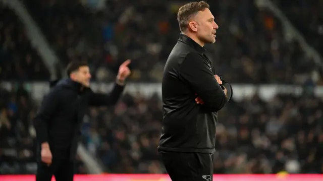 Derby boss John Eustace with Portsmouth manager John Mousinho in the background
