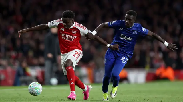 Bukayo Saka is challenged by Idrissa Gueye