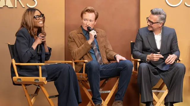 Journalist Jacqueline Coley, Oscars host Conan O'Brien and showrunner Raj Kapoor are seated in directors chairs during a press conference about the ceremony.