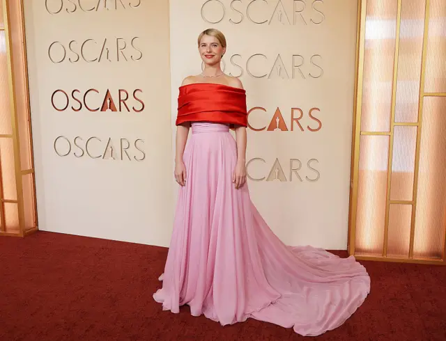 Jessie Buckley on the red carpet wearing a floor-length pink gown and
