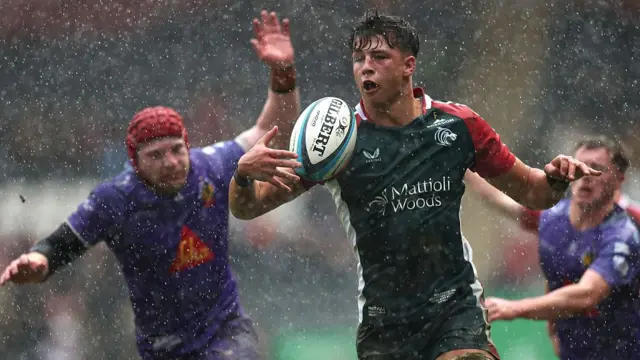Leicester's Harry Palmer tries to catch the ball in front of him with his right arm as rain pours down