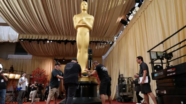 Large Oscars statuette being erected ahead of the ceremony by four men in black T-shirts