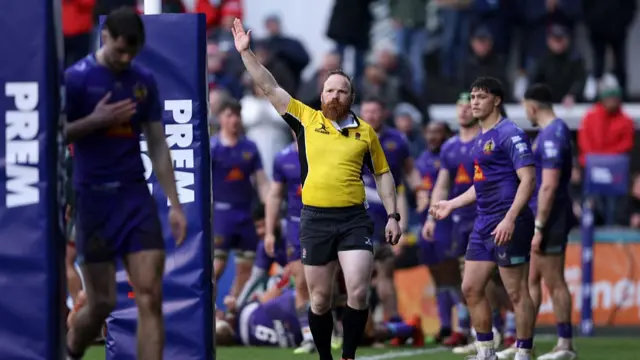 Referee Hamish Smales walks towards the posts with his right arm held up in the air awarding a penalty try