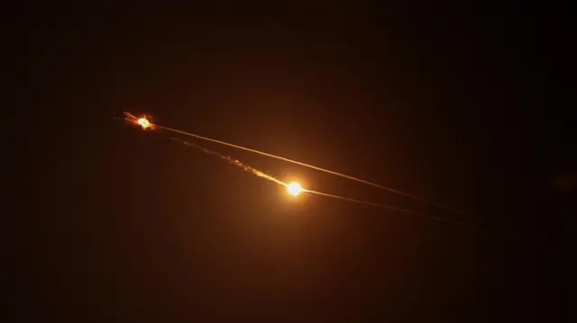 Streaks of light illuminate the night sky during a missile interception.