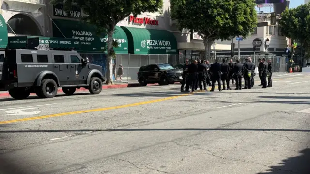 Police huddle on Hollywood Boulevard near a SWAT truck. Fencing is seen on both sides of the street ahead of the Oscars