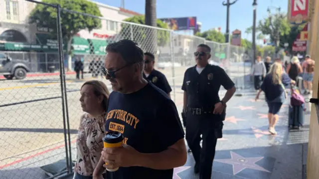 People and police walk along Hollywood Boulevard near where the Oscars will be held. There is fencing and intense security