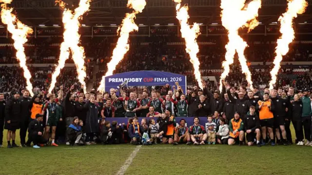 Leicester players stand around the podium and hold the trophy as fireworks go off