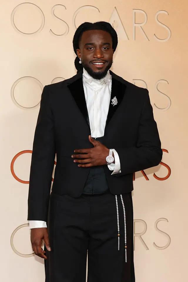 Shaboozey wears a three piece suit adorned with metallic and pear accents