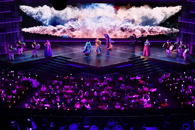 An aerial view of the audience and stage during the performance of Golden. The audience holds up lightbulbs