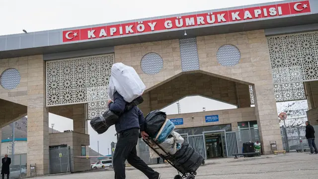 A man, carrying a sack on his back, leaves Iran with his suitcases at the TurkeyIran border in Van, Turkey, on March 14, 2026,
