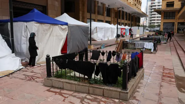 Clothes of displaced people hang on a fence next to tents they use as shelter in Beirut