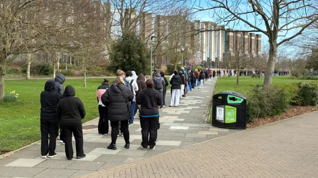 A long queue of people on a university campus.