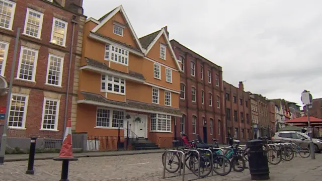 Partou King Street, seen from King Street. It is a large, old building, with orange rendering and white windows. There are bikes parked outside, some of them with children's bike seats.