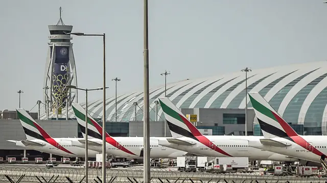 Passenger planes with red, green and black tails sit on the tarmac at Dubai International Airport in Dubai on March 11, 2026.