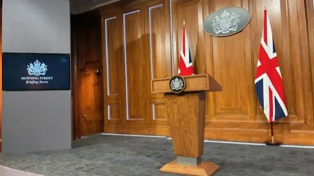 Podium on stage with UK flags behind.