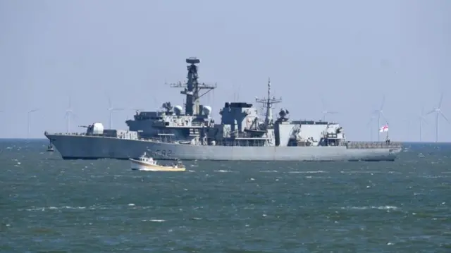 A Royal Navy Type-23 frigate at sea - it is a grey warship with multiple antenna and communications equipment with a prominent forward gun