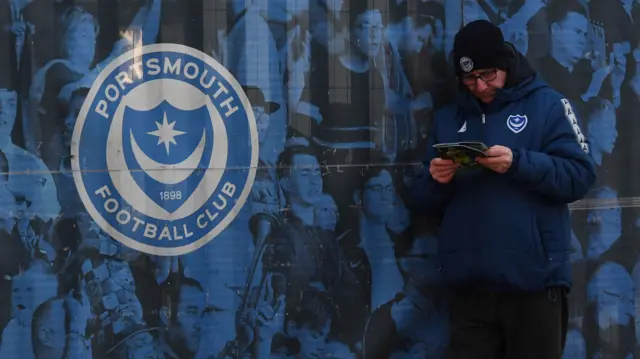 A Portsmouth fan reads the matchday programme