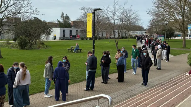 A long queue of people on a university campus.