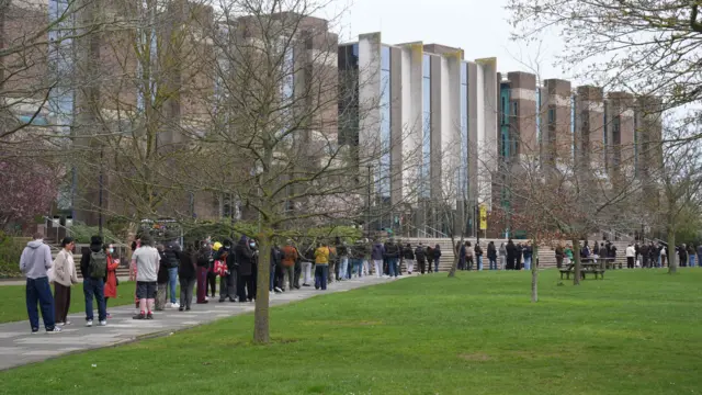 A long queue of people outside a big building.