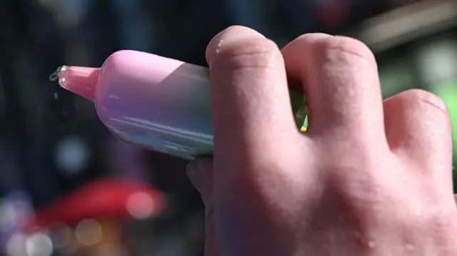 A close up of someone's hand holding a vape pen