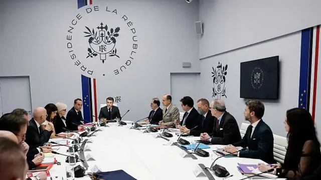 The French cabinet sits around a large oval table with President Emmanuel Macron at the head