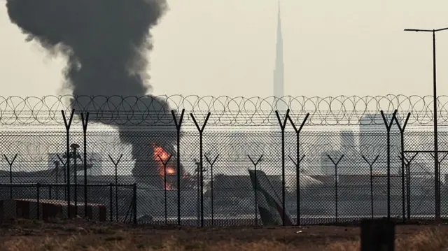 Smoke rises from a fire seen through a fence at Dubai airport