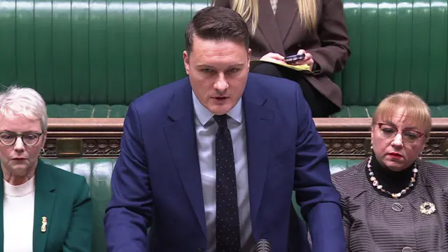 Health Secretary Wes Streeting in the middle of speaking to the House of Commons at the front in front of the green benches