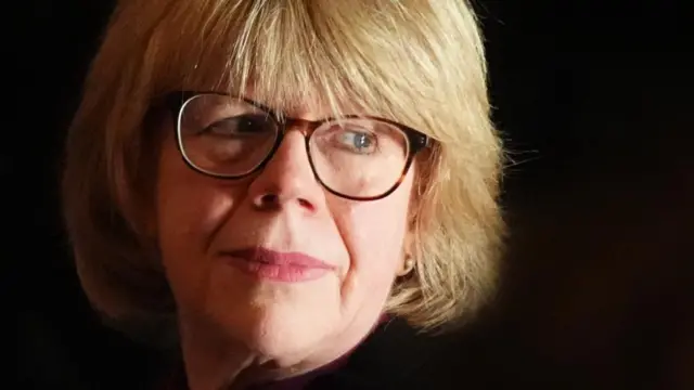 Close up of Archbishop of Canterbury Dame Sarah Mullally. She has on glasses and is tilting her head and looking over her shoulder
