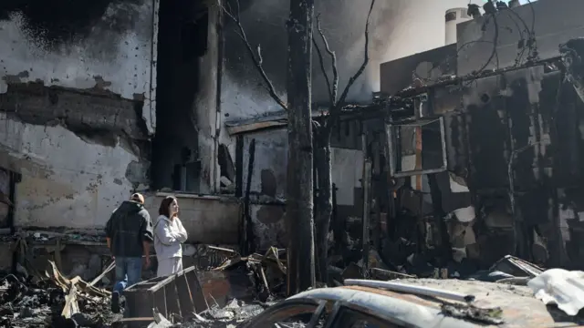 Residents in the Israeli town of Nahariya inspect their house which was burnt by a Hezbollah rocket attack on 17 March