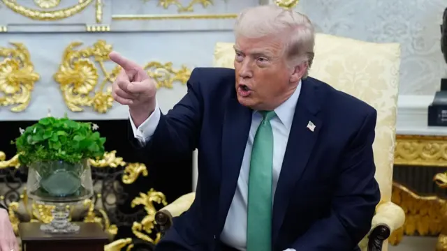 Donald Trump points his finger as he wears a green tie in Oval Office