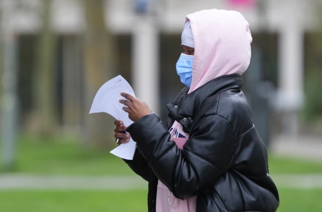 Students wearing face masks queue outside a university building to collect antibiotics