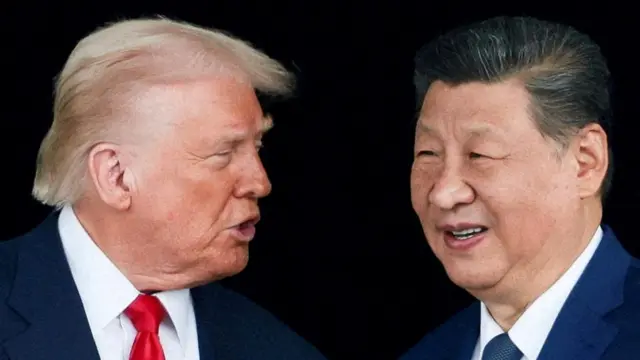 President Trump, in a white shirt and red tie turns his head to speak to President Xi Jinping who wears a navy blue blazer and tie.