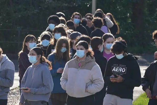 People wear face masks in queue outside