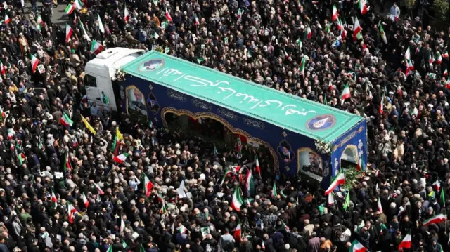 A lorry passes through the crowd as part of the funeral procession