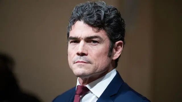 Close up photo of Joe Kent, former director of the National Counterterrorism Center. He is wearing a blue suit over a white shirt and a wine-coloured tie