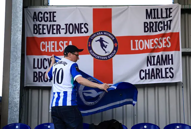 Brighton fan hangs a flag in the away end at Kingsmeadow