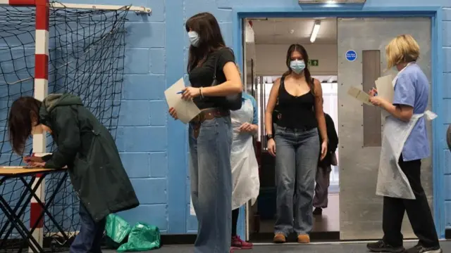 Students wait in line inside a sports centre