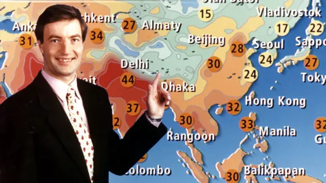A younger David Braine points at a weather map of Asia during a forecast