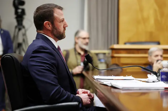 Mullin sits at a table looking forward