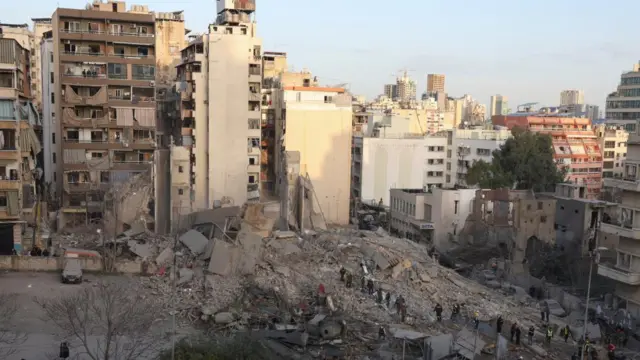 Emergency personnel work at the site of a collapsed building, in the aftermath of an Israeli strike