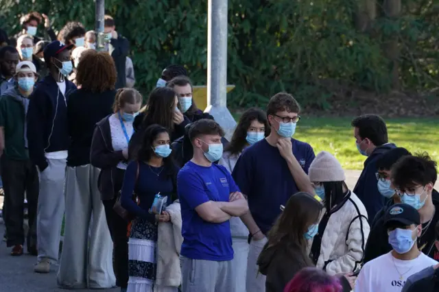 People wear face masks in queue outside