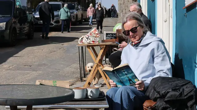 A lady reads a book in the sun