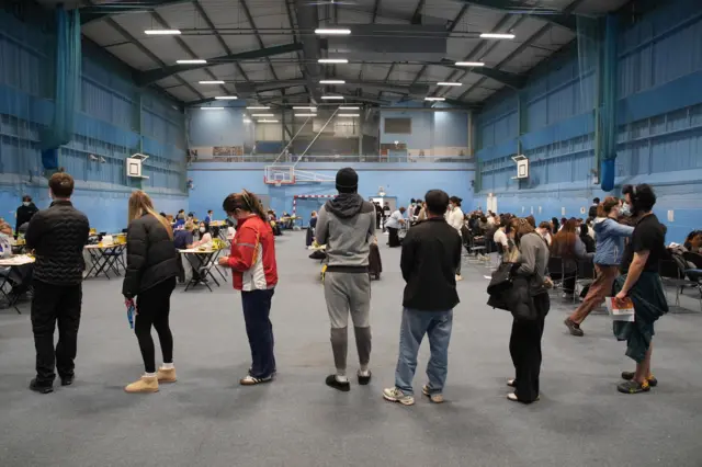 Students wait to receive vaccines and antibiotics from medical staff in the sports hall at the University of Kent campus in Canterbury